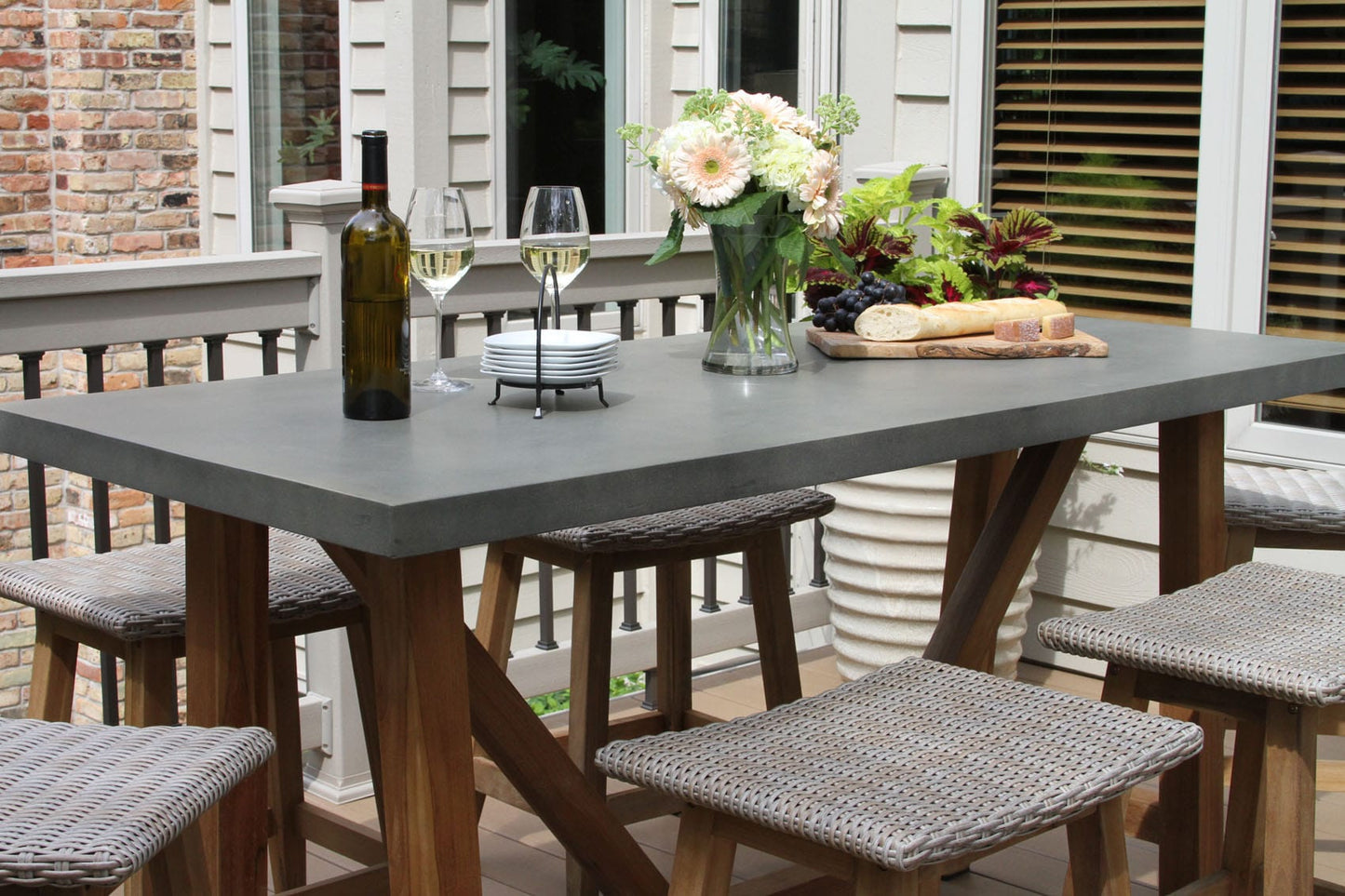 Outdoor Interiors TNA6425 Composite Balcony Height Dining Table with Teak Base and TNA5475 Teak & Ash Wicker Saddle Stools 7pc Set